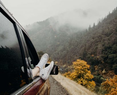 Une personne sortant les pieds de la vitre de la voiture